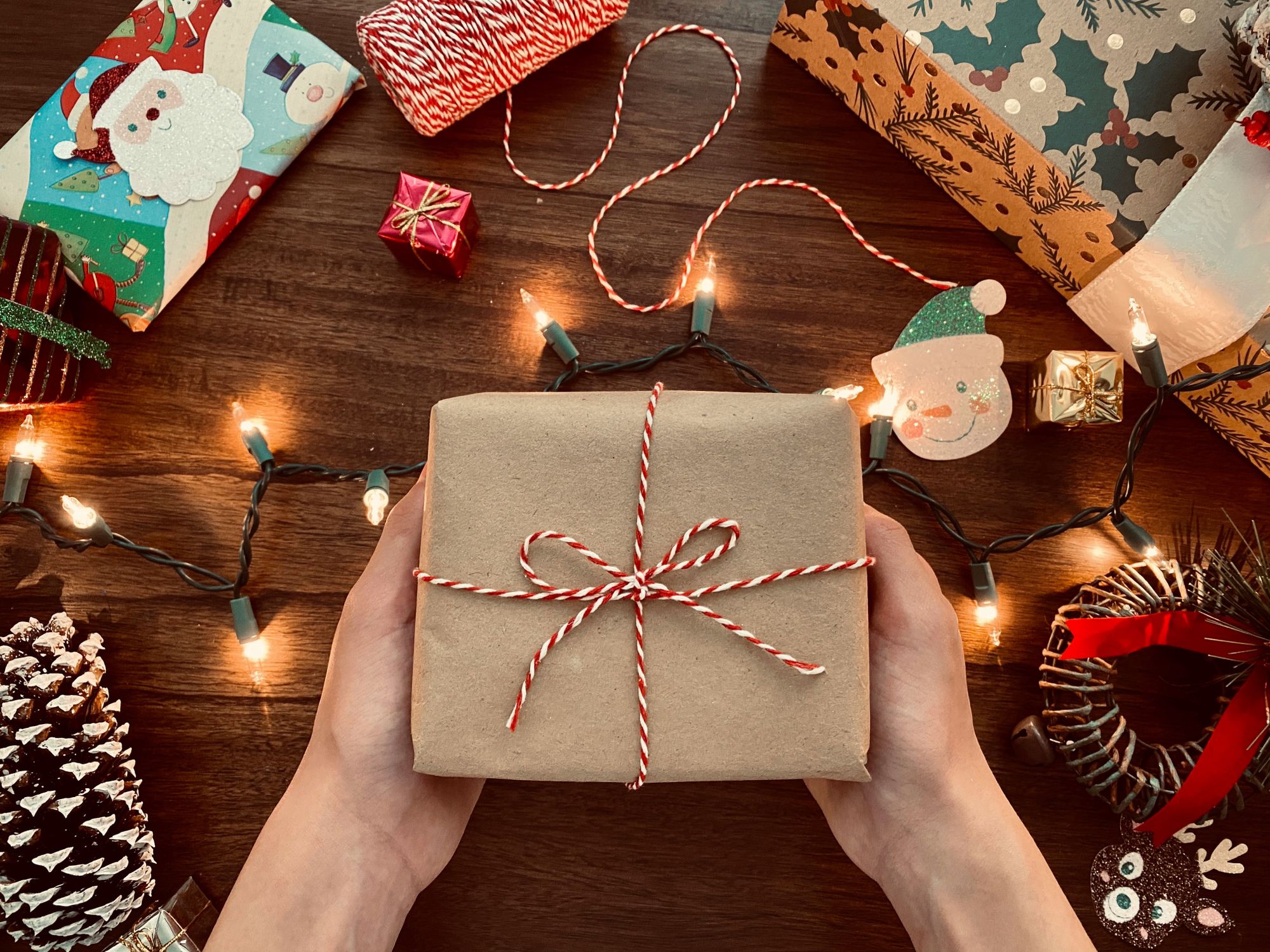 box wrapped in brown paper as a gift for christmas, tied in a ribbon with fairy lights on the table