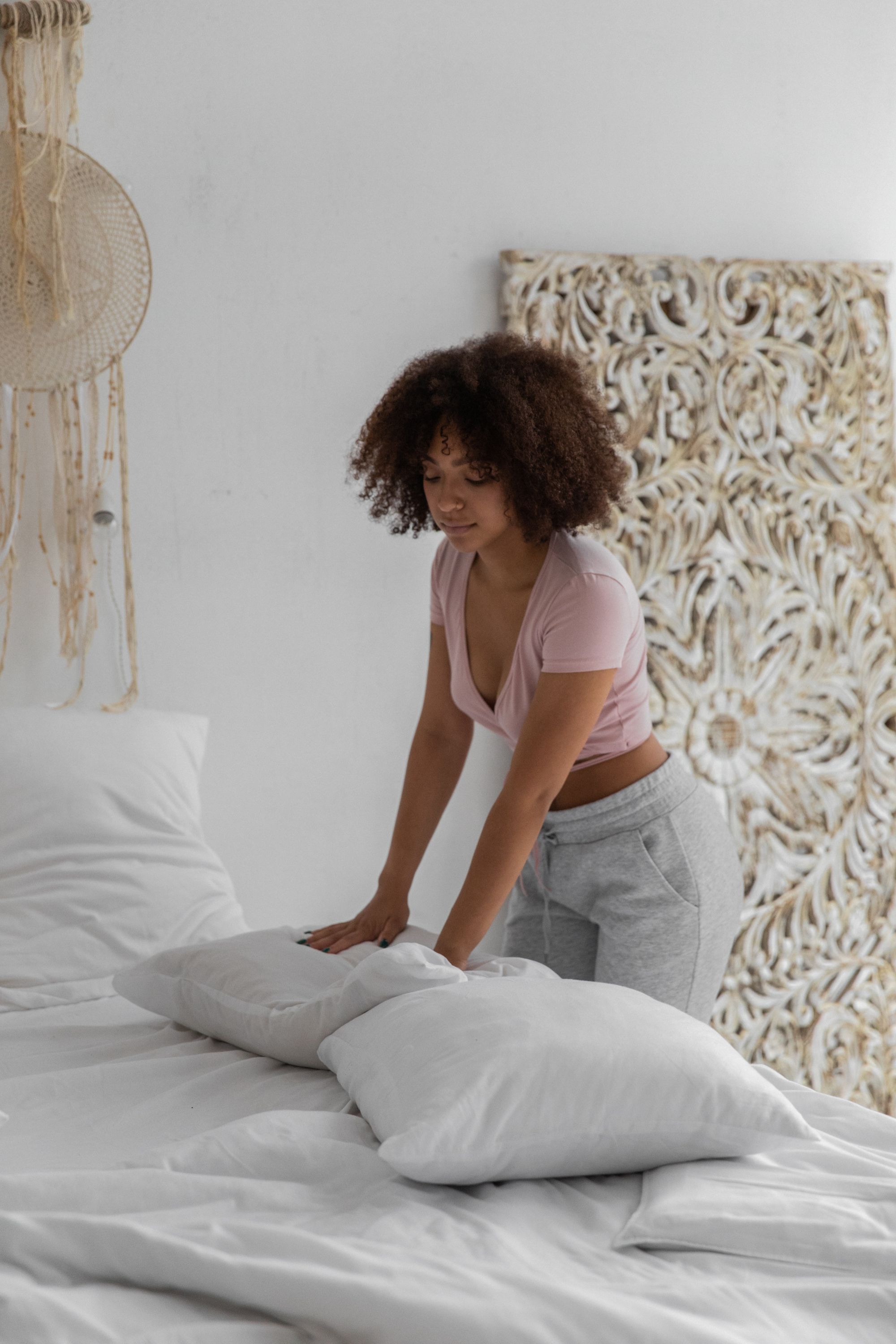 woman in pajamas making her bed