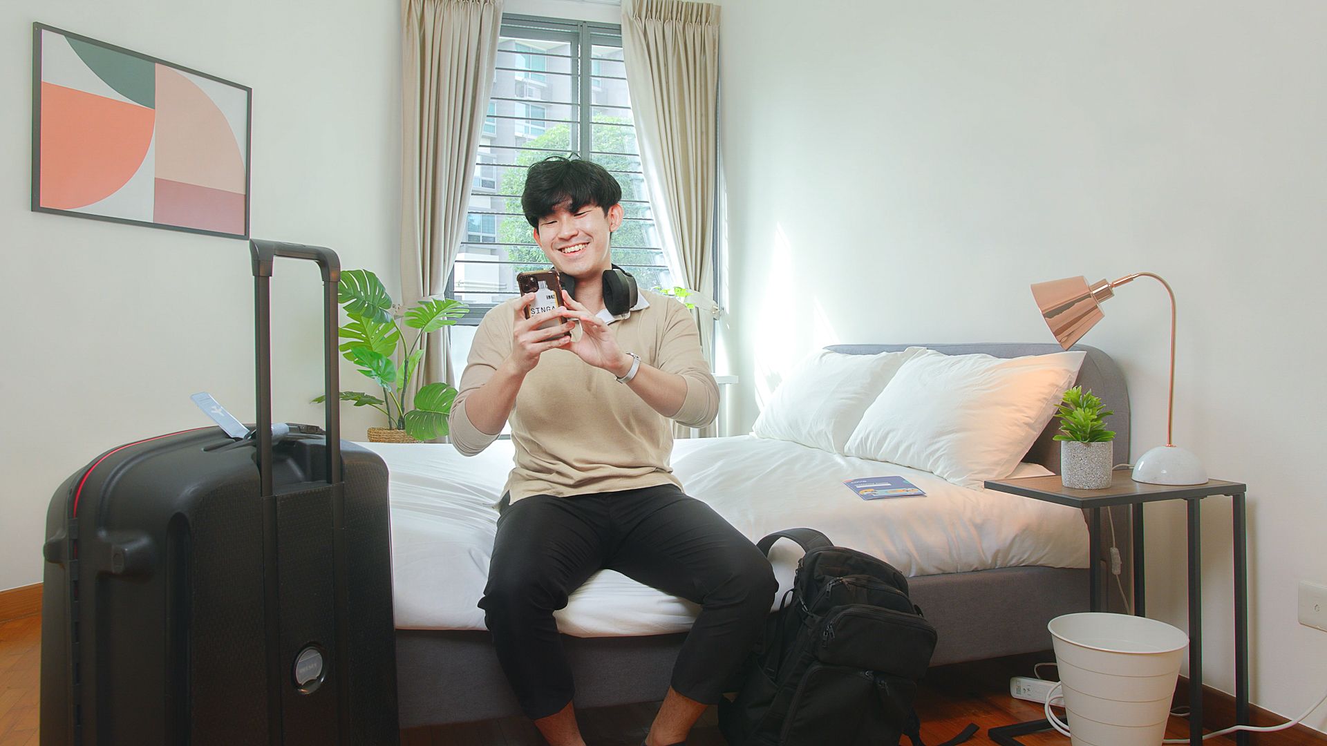 asian man looking at smartphone on his bed