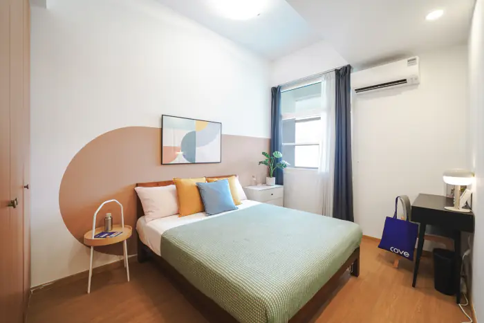 Master ensuite room with a queen bed, soft pastel walls and a desk at The Bayron