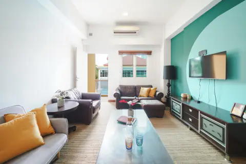 Living room with a sofa and a teal feature wall in a one-bedroom apartment at D'Arena