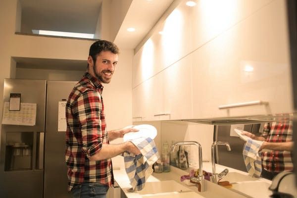 man washing and wiping the dishes