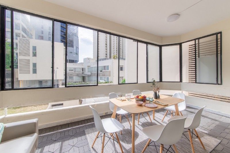 dining area at Hock Mansions, with dinner table that has 6 chairs and a sofa set by the side, overlooking the buildings of the neighbourhood